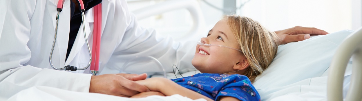 Una niña sonríe a una médico que le agarra la mano