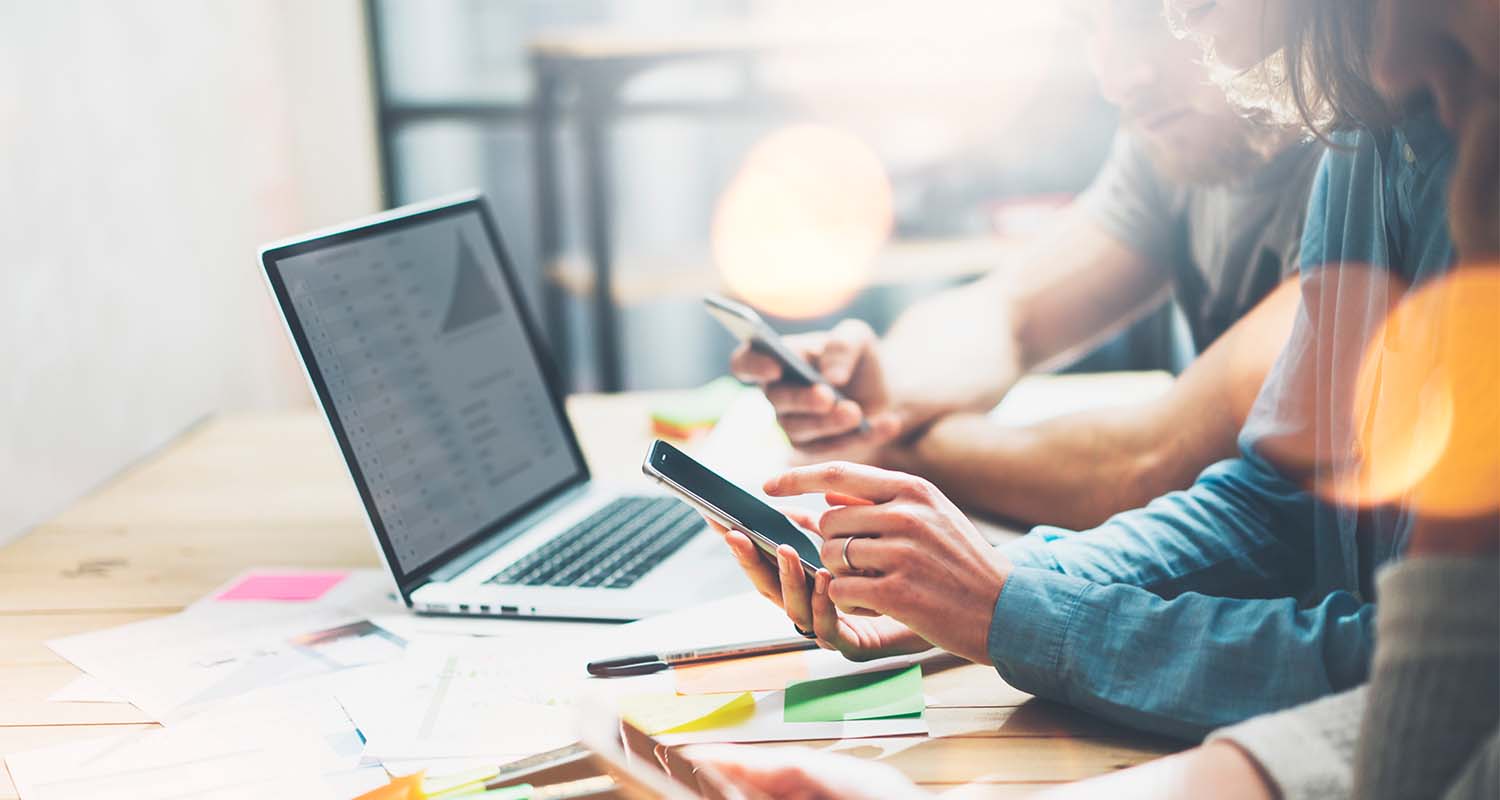 Jóvenes trabajando con sus smartphones y un portátil