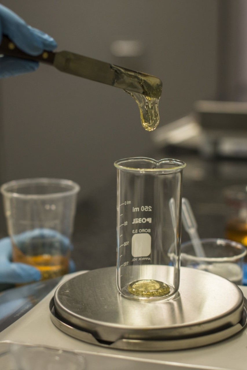 Gota de lubricante cayendo en vaso en laboratorio