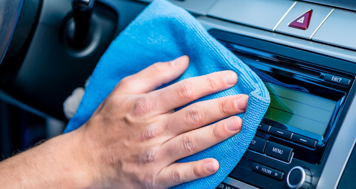 A person cleans the interior of their vehicle with a blue cloth
