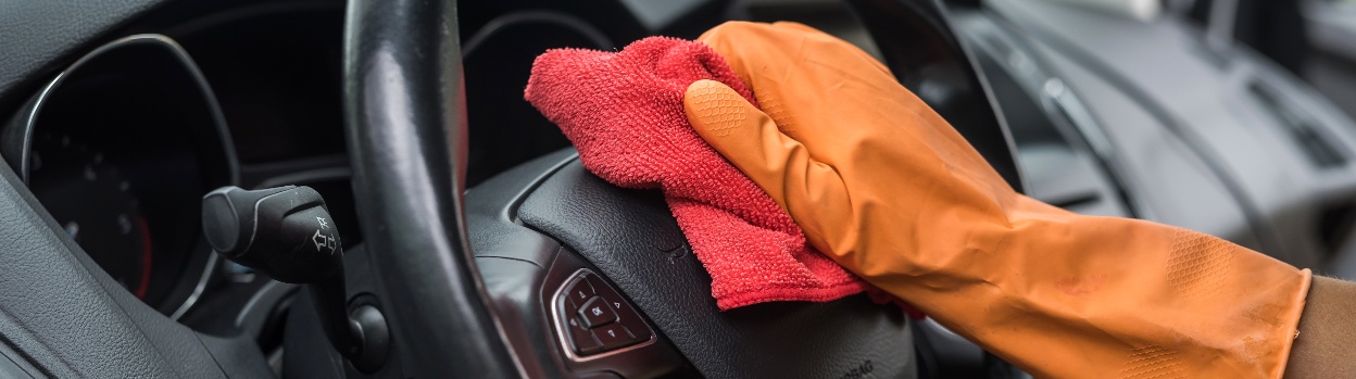 A person cleans the steering wheel of their vehicle