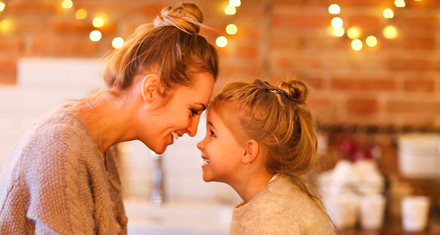 Mother and daughter exchange a glance with lights in the background. Multi-energy provider.
