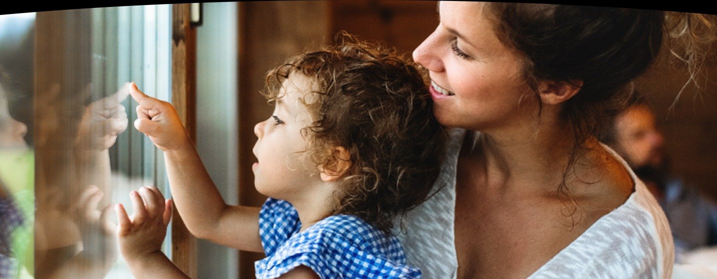 A mother and her son play with the reflection in the glass