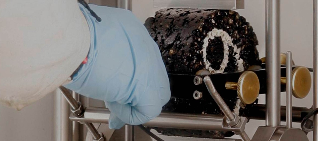 Gloved hand testing asphalt