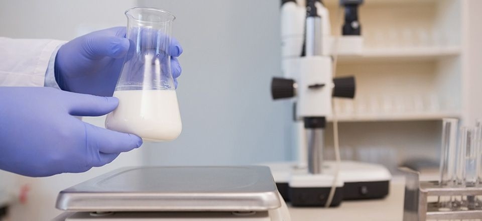 Some hands hold a flask with a white liquid