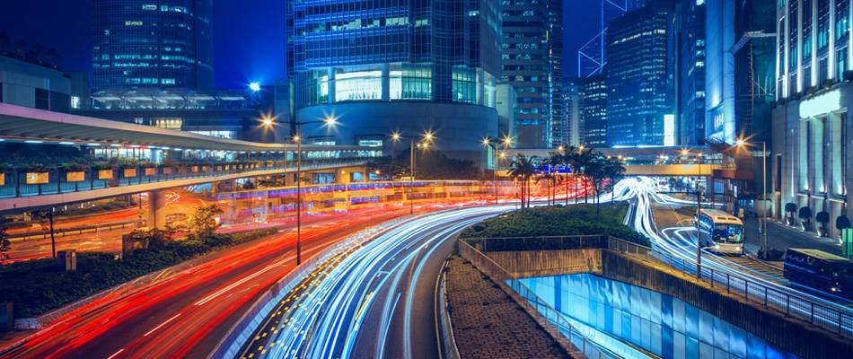 Night-time view of a road lit up by the city&rsquo;s lights