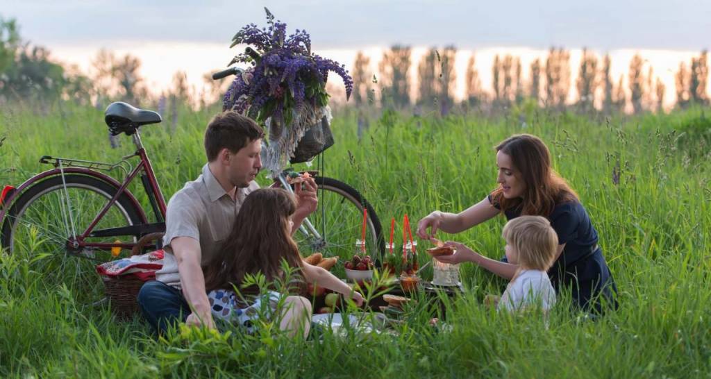 A family picnicking next to a bicycle with a bouquet of flowers