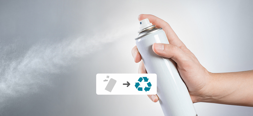 A hand squeezes the nozzle of a spray can