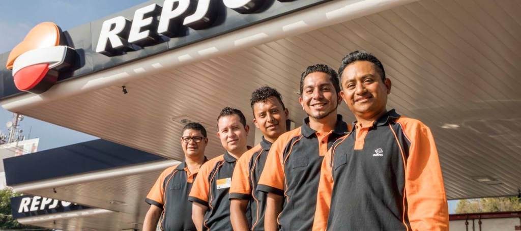 Varios trabajadores de una estación de servicio Repsol en México posando para una foto al lado de una estación de servicio sonriendo