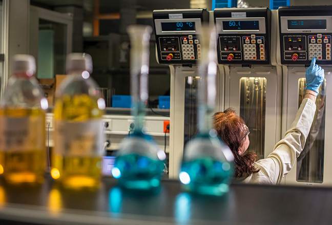 Repsol en el mundo México. Mujer en un laboratorio tras unas probetas azules y unos frascos desenfocados