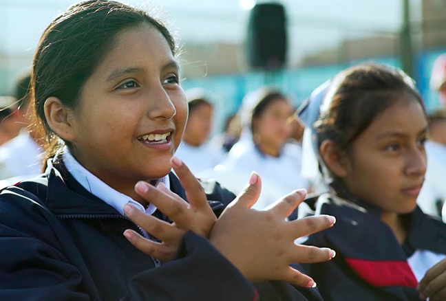 Repsol en el mundo Perú. Niñas haciendo gestos con las manos mirando hacia la derecha de la imagen