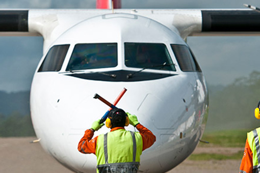 Un operario de tierra realiza indicaciones a un avión 