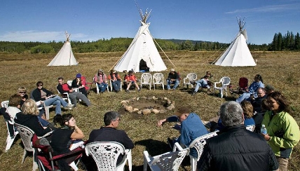 Repsol in Canada. Group of people sitting around an indigenous teepee 