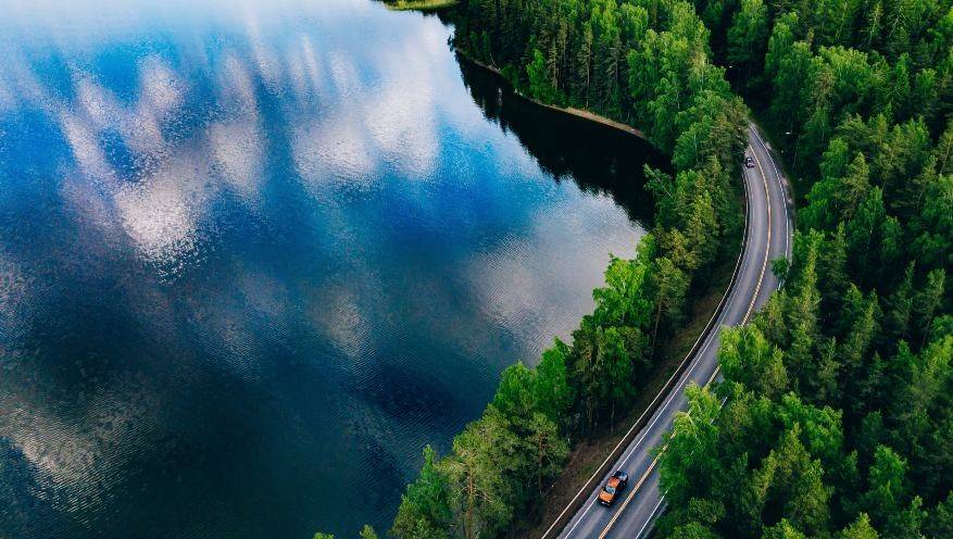 Coche en una carretera frente a un lago
