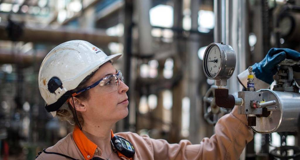 A woman wearing a protective helmet at an industrial complex