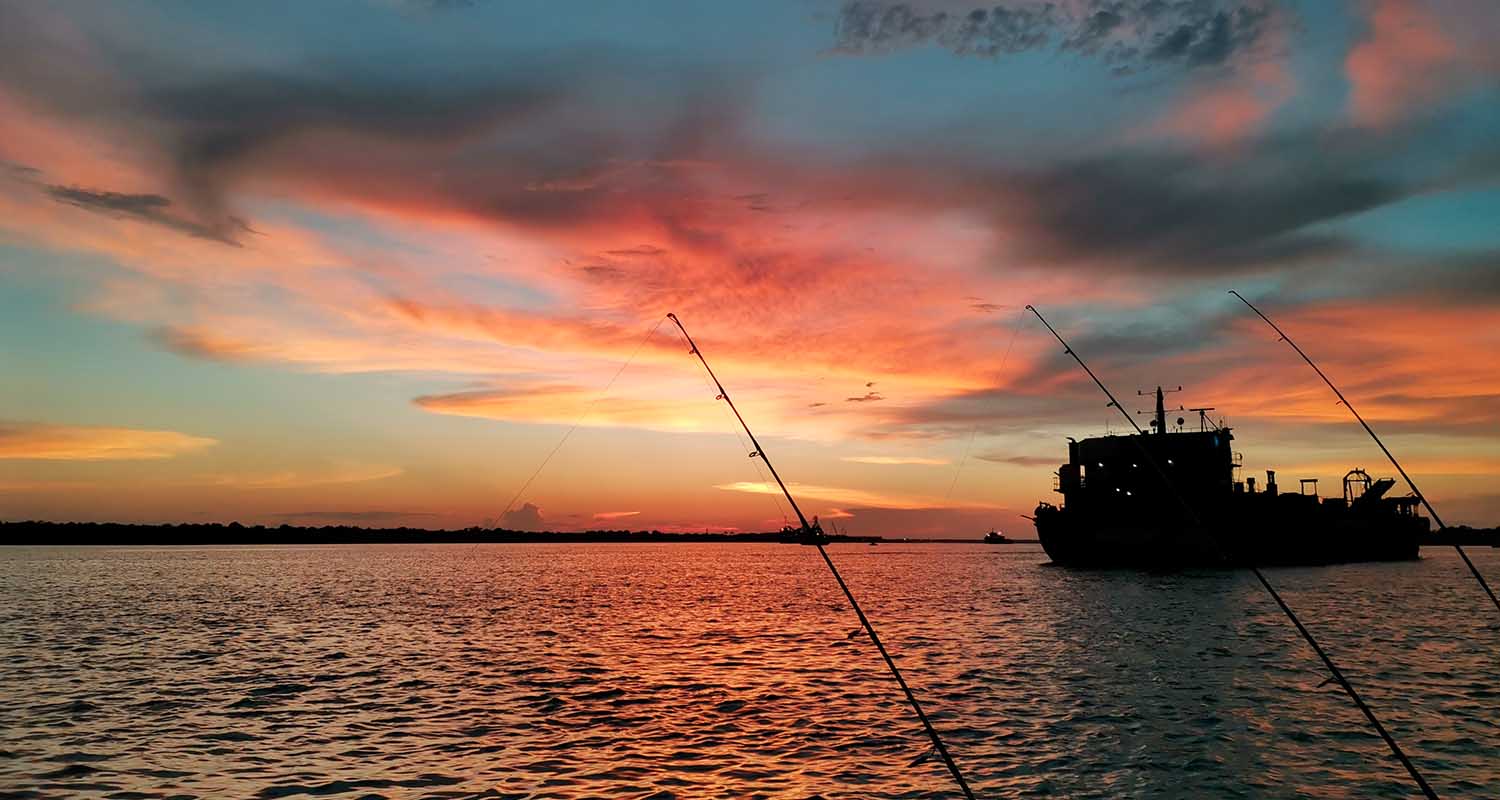 Communities and shared value. Landscape of a boat and fishing rods at sunset