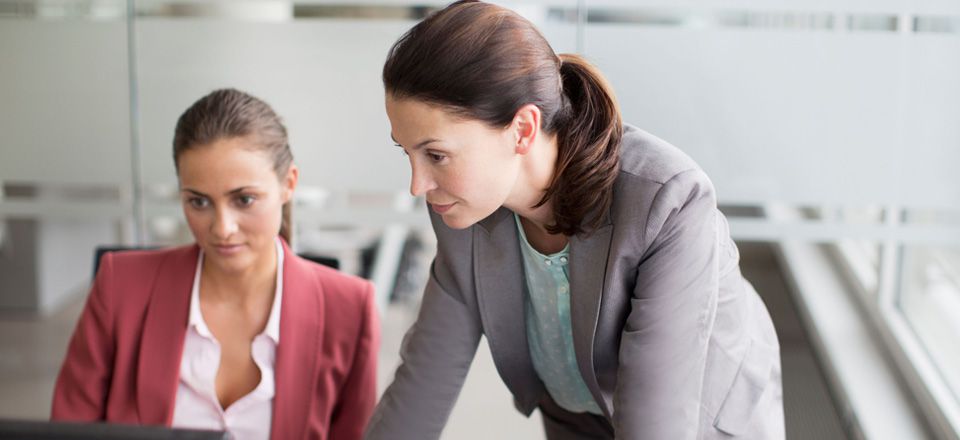 Dos mujeres reunidas consultan un ordenador 