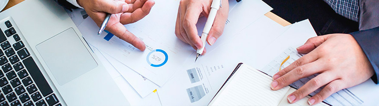 A table with several papers with economic data, balance sheets, and a laptop, Financial policy