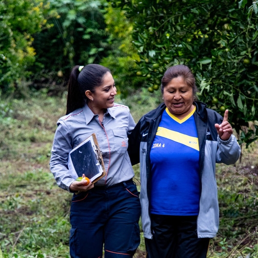 Empleada Repsol y mujer boliviana caminan agarradas 
