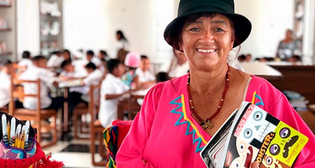 A woman in a hat smiles at the camera