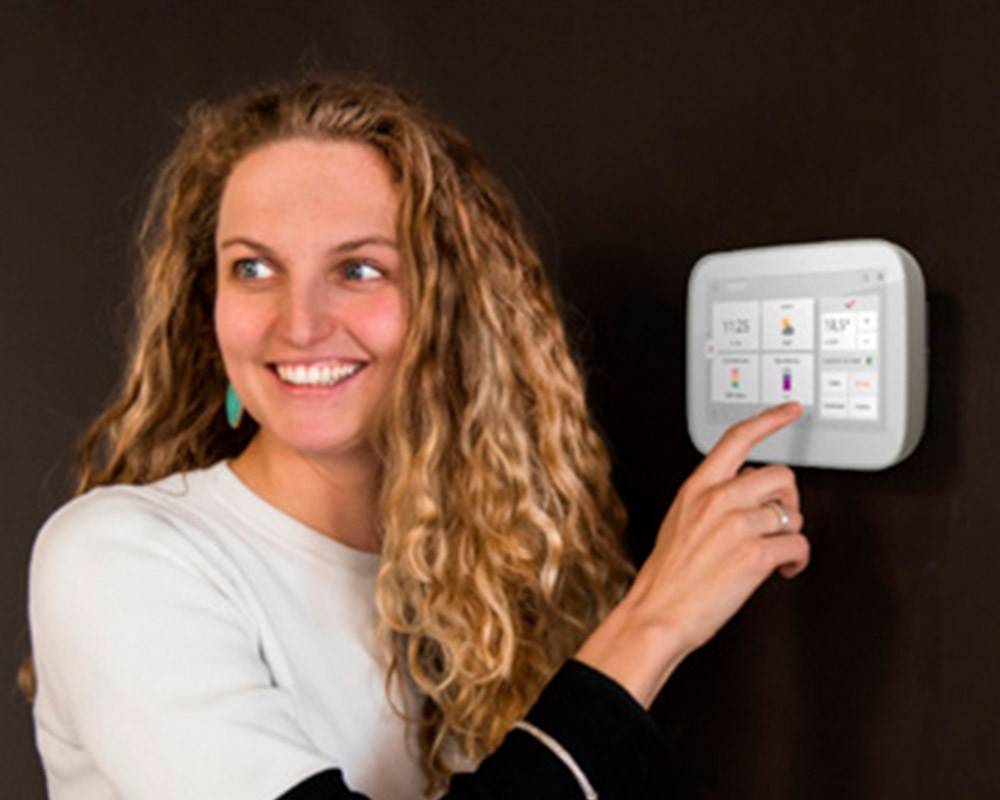 A woman adjusts a digital thermostat