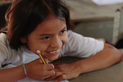 A little girl at the desk smiles in Bolivia.