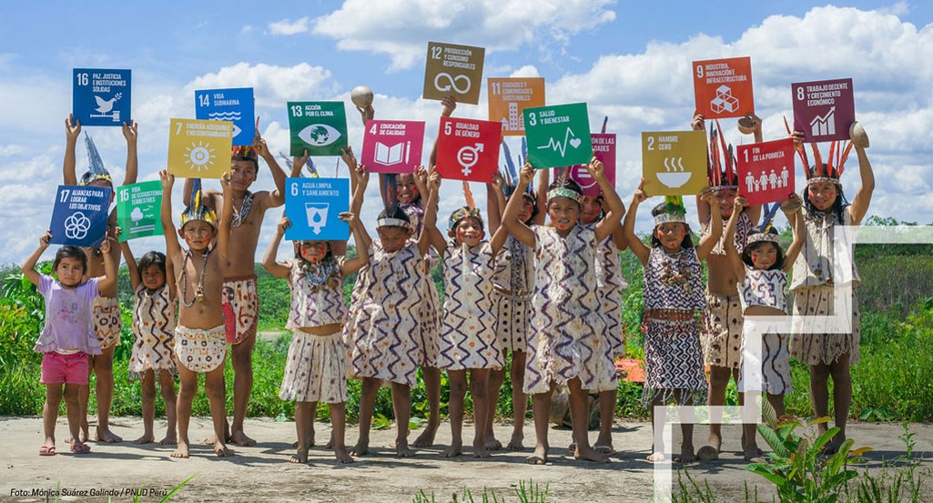 Niños levantan carteles con los logos de los ODS