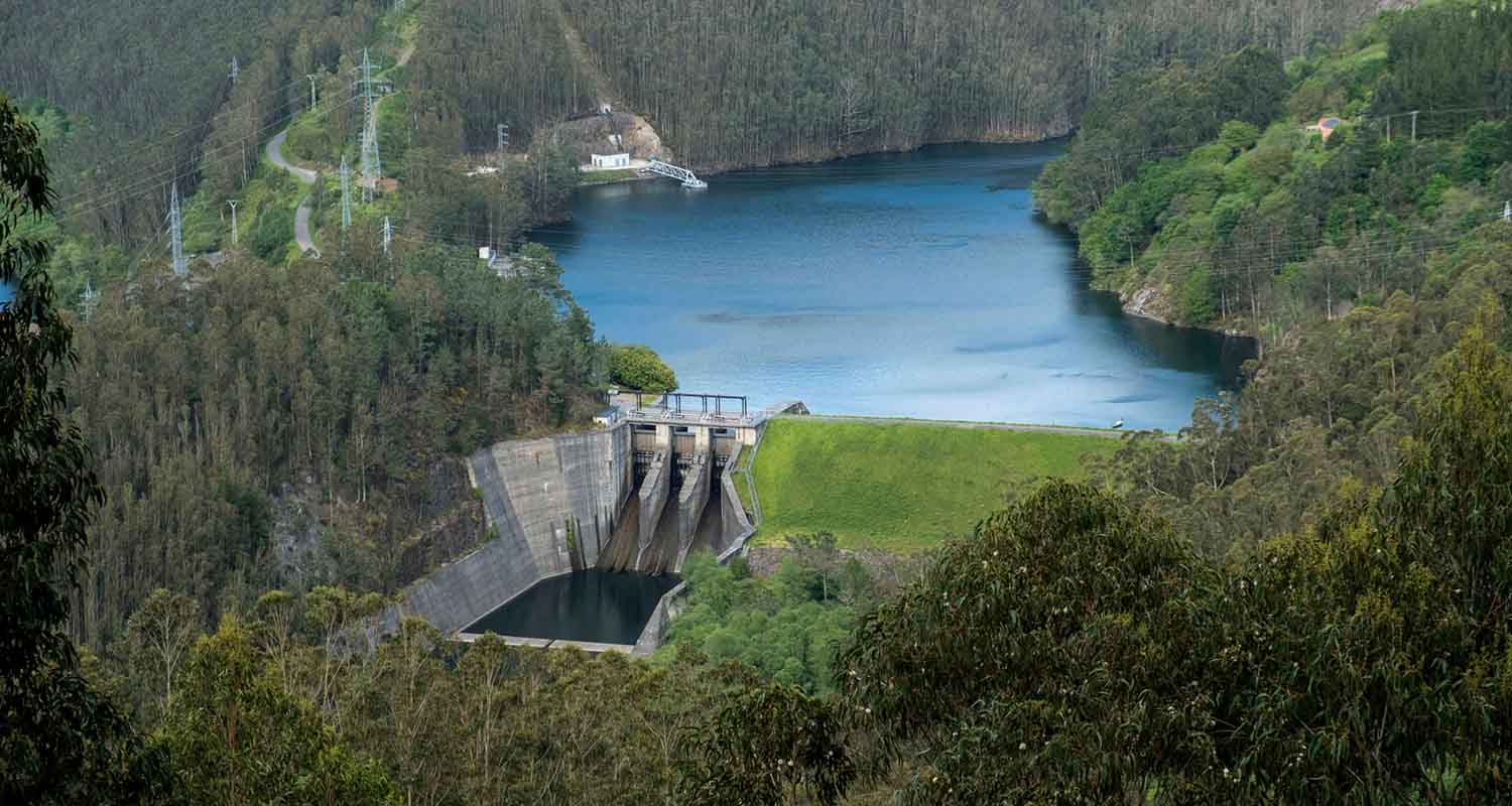 Hydraulic dam surrounded by tree-lined mountains