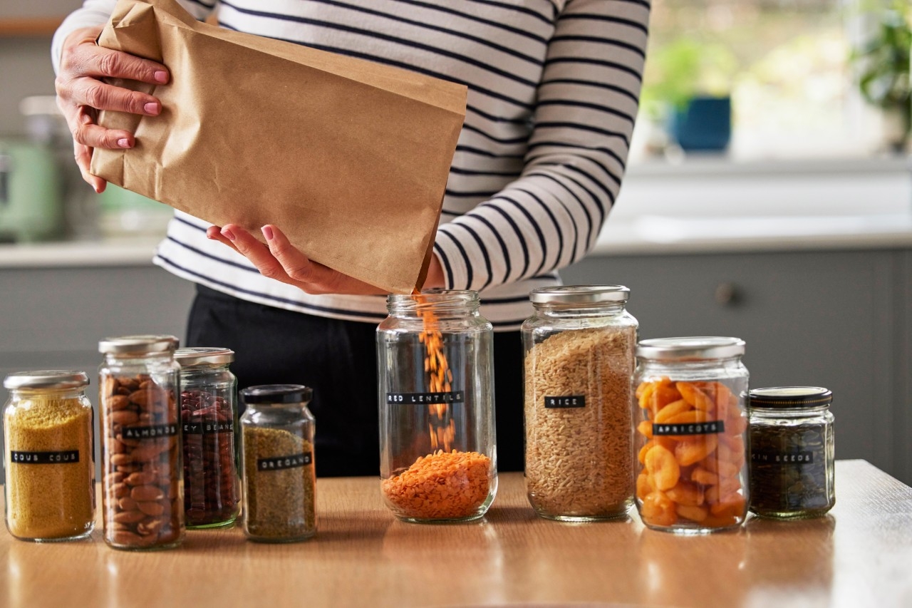 una mujer rellena tarros con productos comprados a granel, un ejemplo de consumo responsable