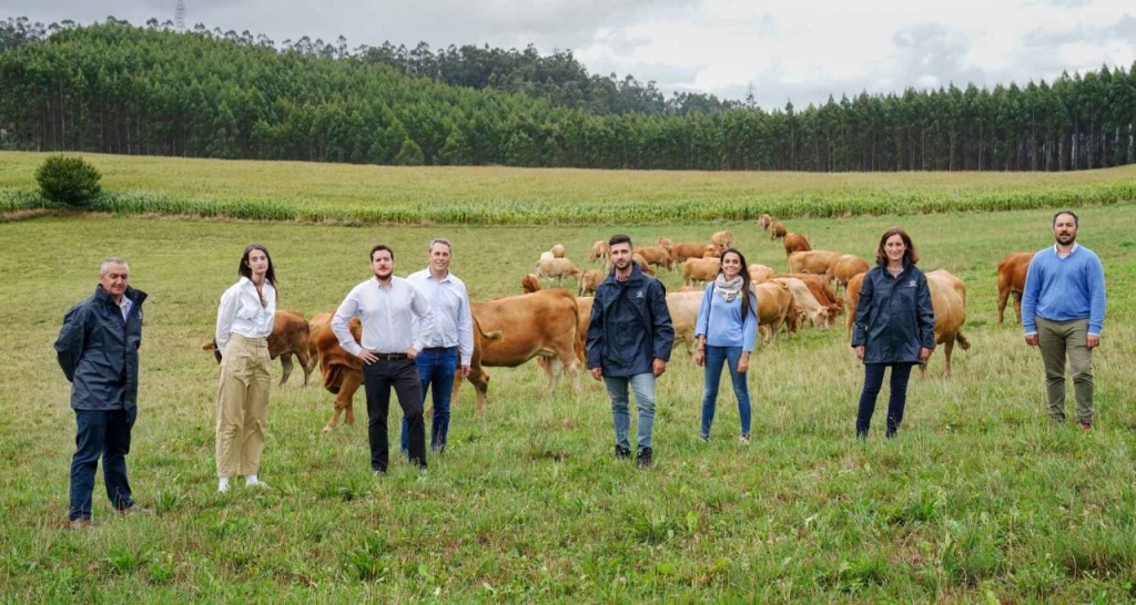 Varias personas del proyecto posando en un campo con vacas de fondo