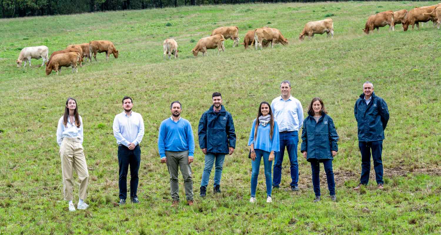 Varias personas del proyecto posando en un campo con vacas de fondo