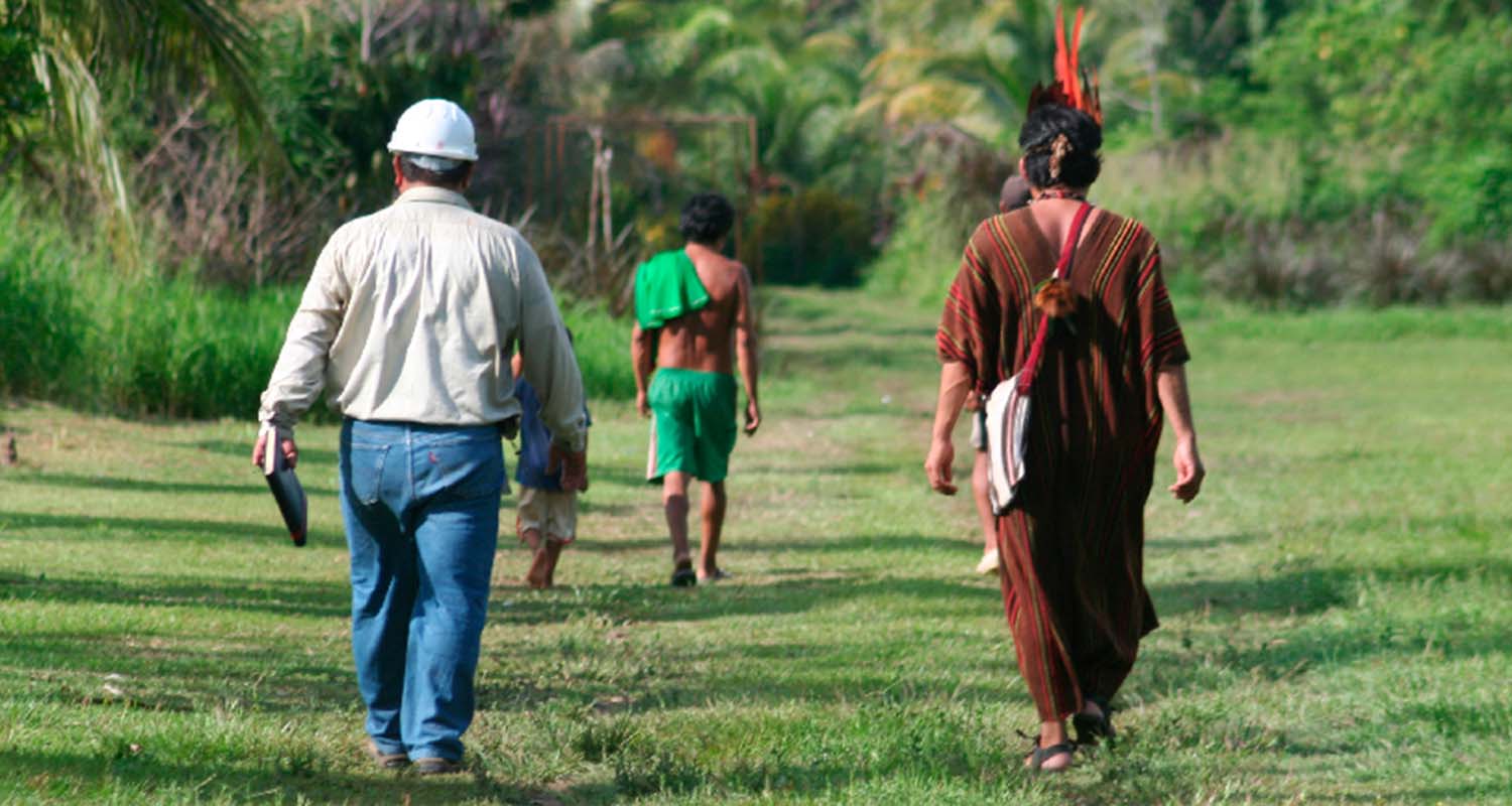 A Repsol employee walking next to two indigenous people