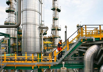 Worker on ladders at an industrial complex