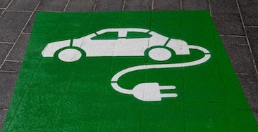 Símbolo de coche eléctrico pintado en la acera